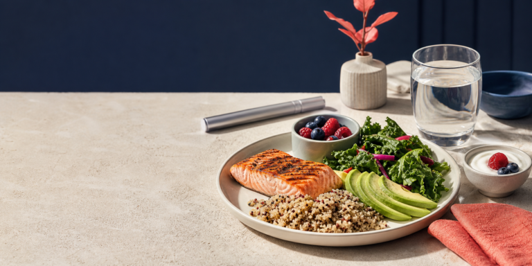 Balanced GLP-1 nutrition meal with salmon, quinoa, vegetables, avocado, berries, yogurt, water, and an unbranded medication pen